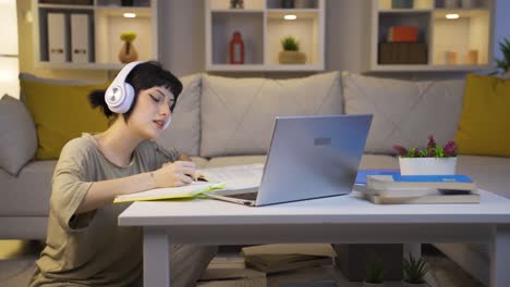 Female-student-listening-to-music-and-studying-at-night.